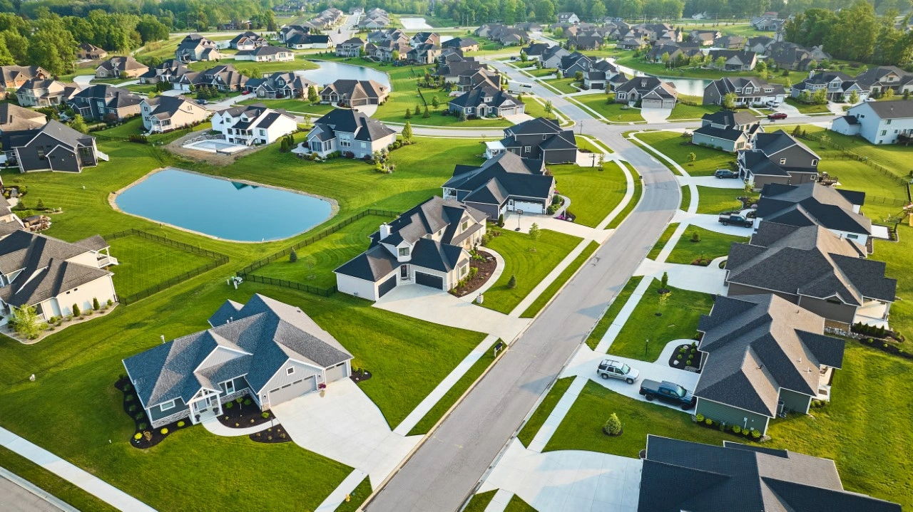 A view of houses from above, with water in the background.