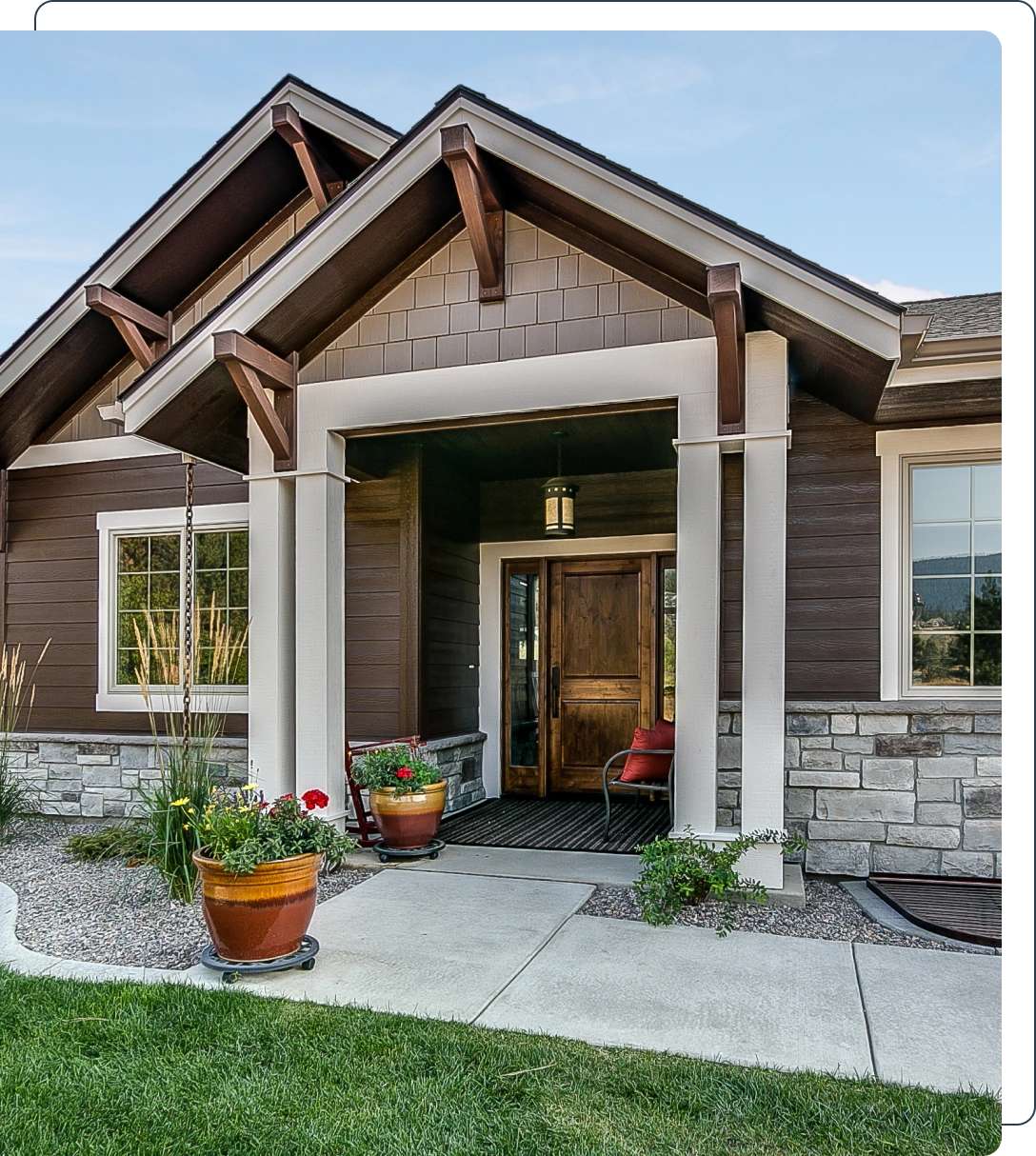 A house with a porch and plants in front of it.